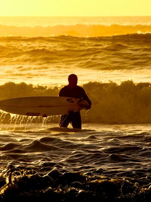 poster Un homme tenant une planche de surf dans l'océan